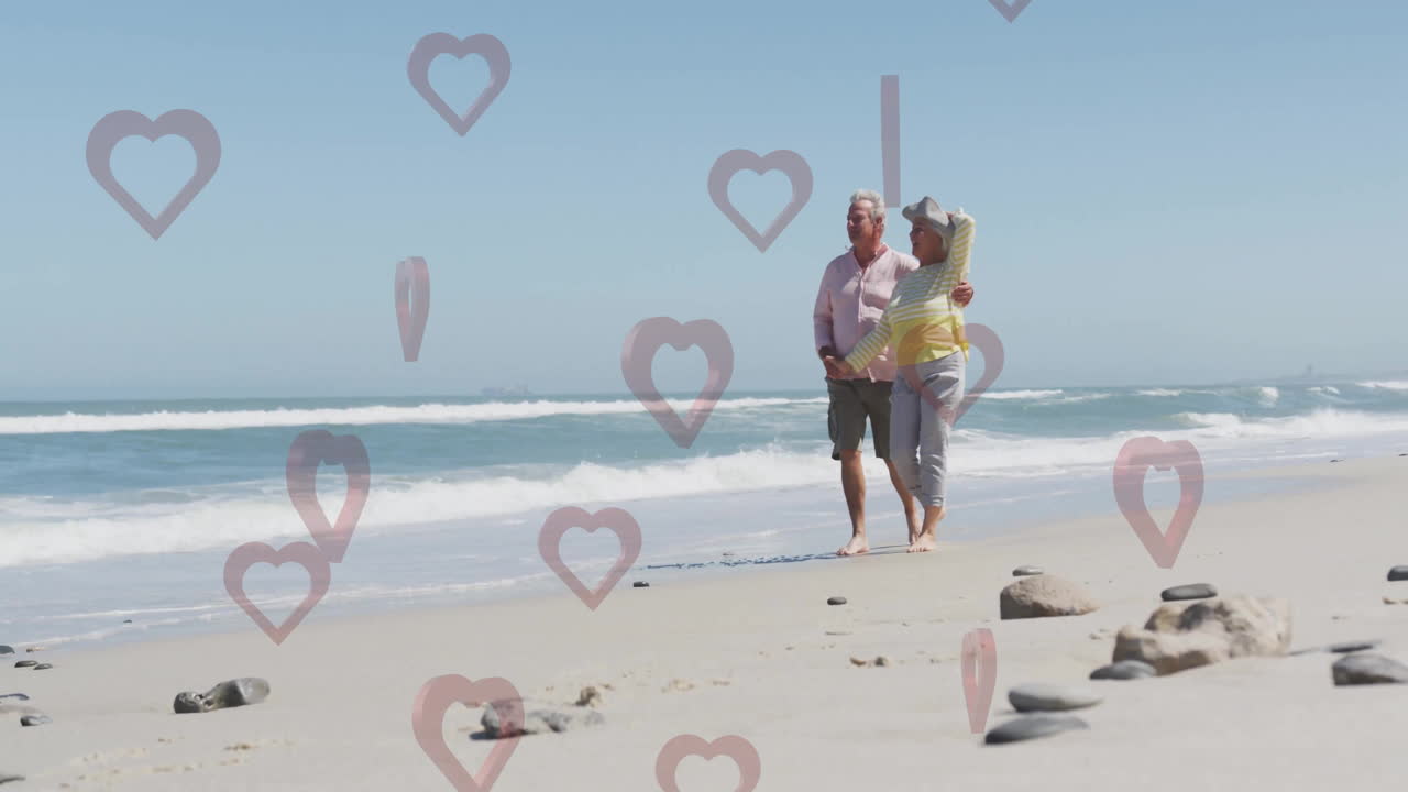 Walking on beach, elderly couple with animation of heart shapes floating