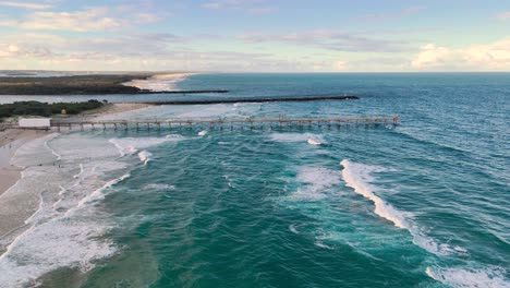 las olas del océano golpean el muelle en la costa de oro.