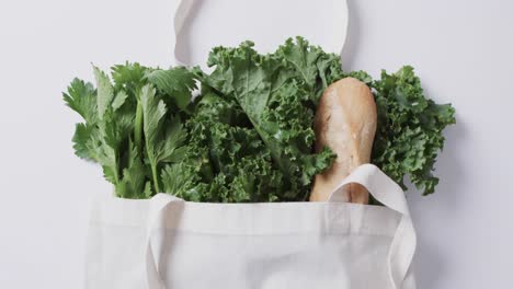 video of white canvas bag with parsley, kale and baguette, copy space on white background