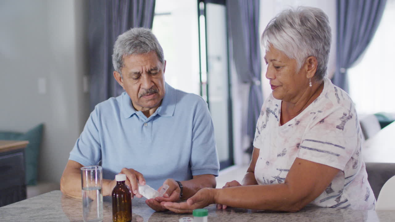 Senior biracial couple talking and taking pills