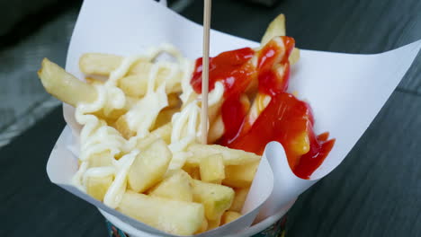 patatas fritas calientes caen sobre papel blanco para absorber el aceite después de cocinar y verter sal dispersa con salsa