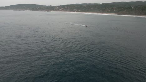 Aerial-view:-Tour-boat-speeds-past-Mazunte-beach-in-coastal-Mexico