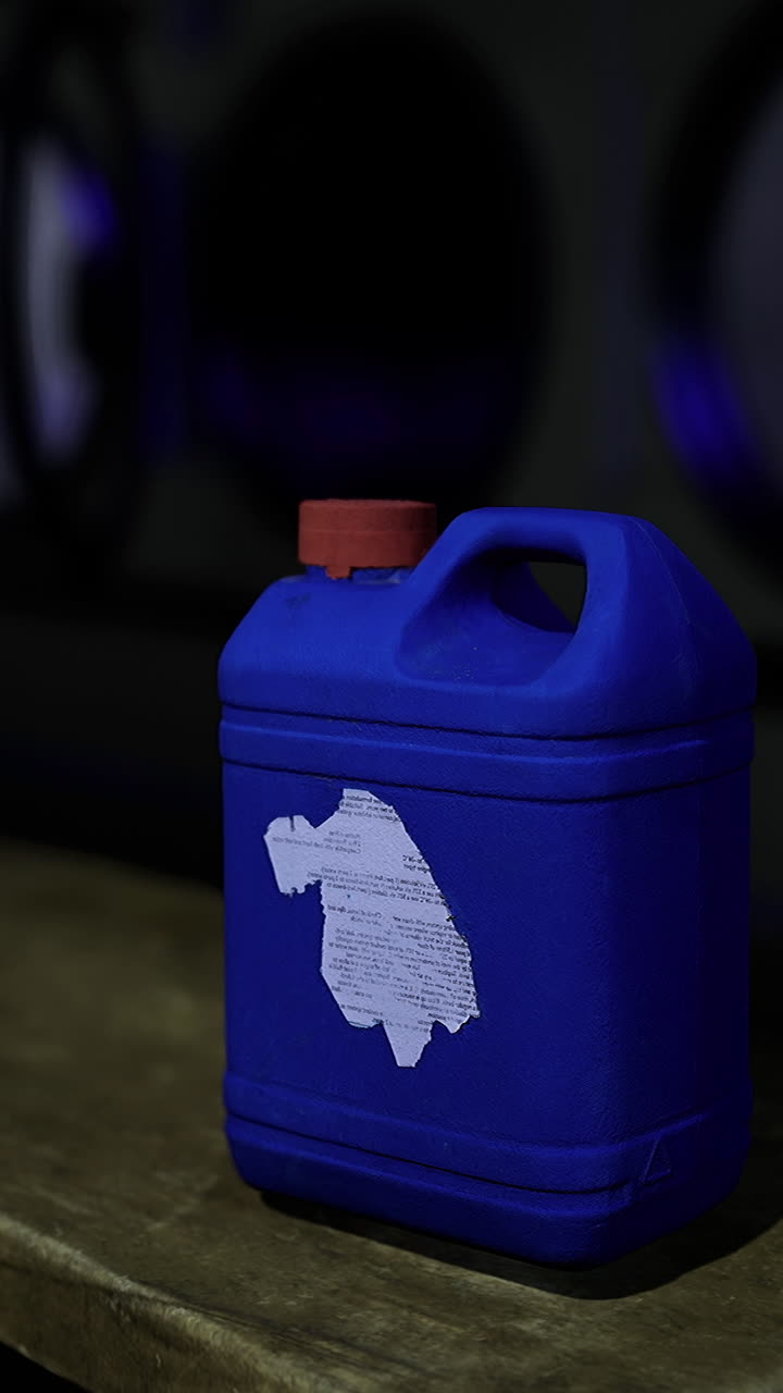 Modrá nádoba na dřevěném stole v tlumeně osvětlené prádelně v noci
