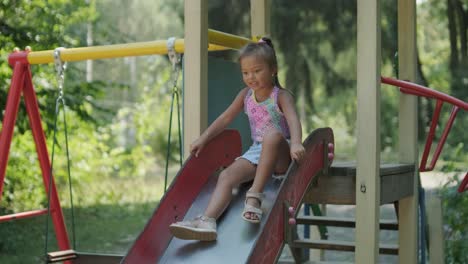 pregnant mother watching daughter play on slide at playground