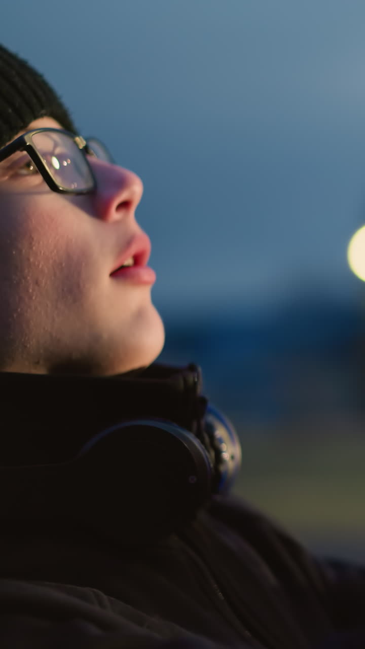 vista lateral de un niño en traje negro y gafas, levantando una pelota con un auricular alrededor de su cuello, el fondo presenta un borrón de reflejo de luz