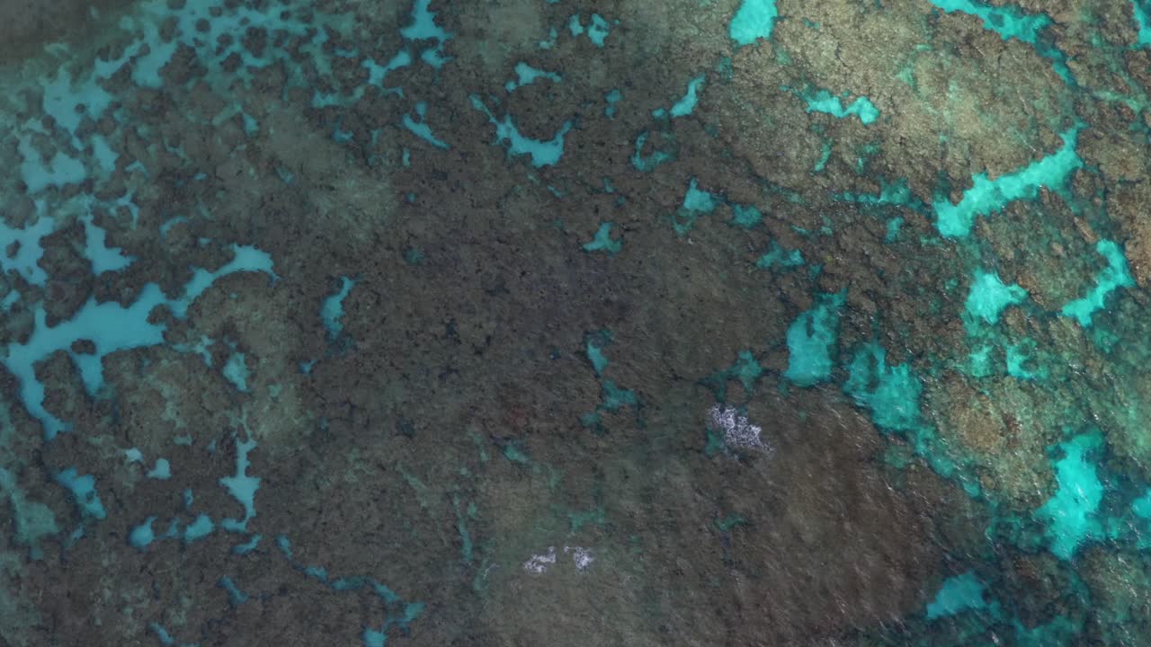 A drone captures a shot of a blue lagoon, showcasing the crystal-clear waters that reveal the stunning underwater landscape while the sun start to shine and light up the water
