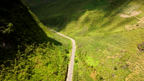 Tham-Ma-Pass,-Ha-Giang-Province,-Vietnam---A-Rider-Navigating-the-Tough-Motorbike-Route-Surrounded-by-Dense-Green-Mountains---Tracking-Shot