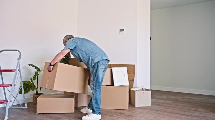 Uomo anziano che trasporta una scatola di cartone nella sua nuova casa