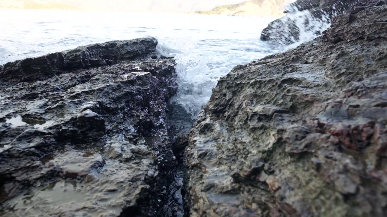 Onde che si infrangono sugli scogli vicino al centro storico di Budva sulla costa del Montenegro, sulla costa adriatica, in un soleggiato pomeriggio al tramonto