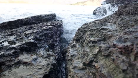 Waves-crashing-into-rocks-near-Budva-old-town-on-the-coastline-of-Montenegro-on-the-Adriatic-coastline-on-a-sunny-sunset-afternoon