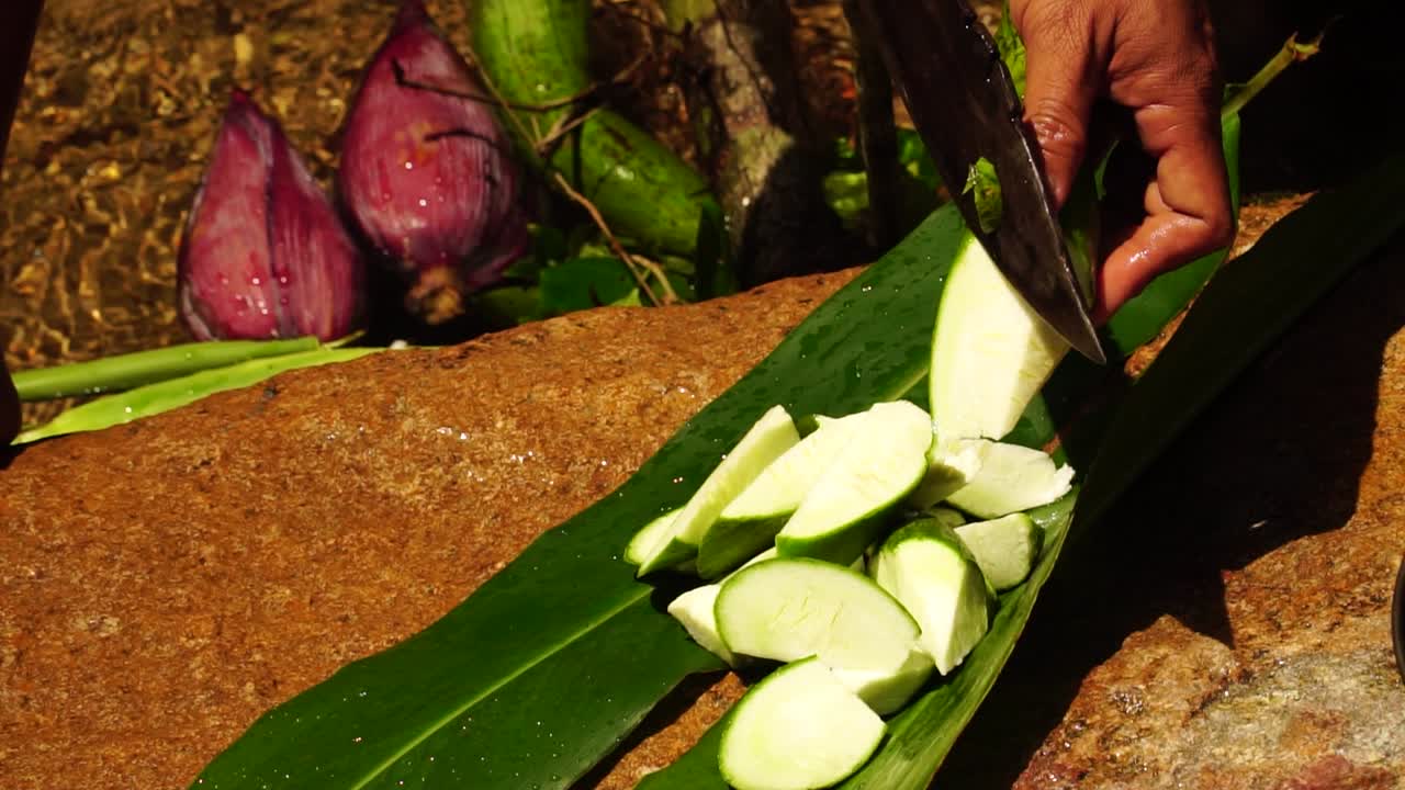 Local guide cutting fresh wax gourd with machete during jungle trek in Vietnam