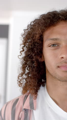vertical video: a young biracial man with curly brown hair gazes forward