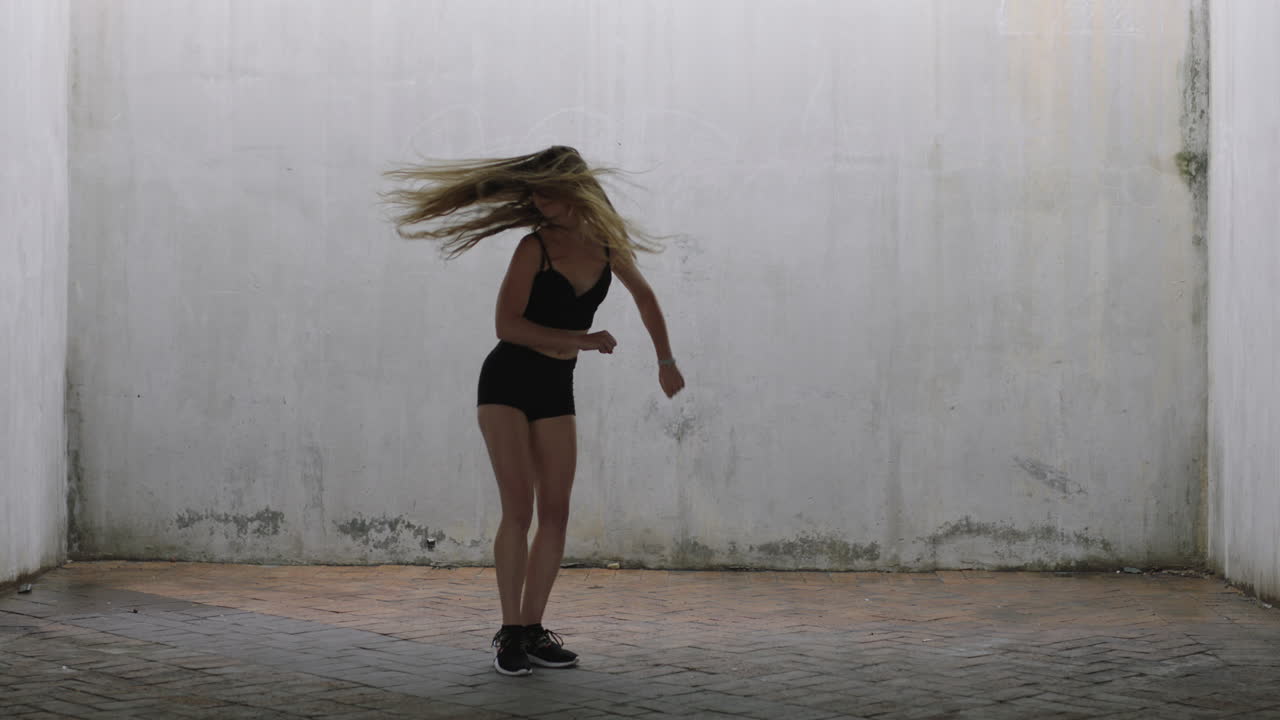 mujer bailarina atractiva joven bailarina de calle caucásica realizando movimientos contemporáneos disfrutando de la expresión de la danza moderna practicando en un almacén grungy