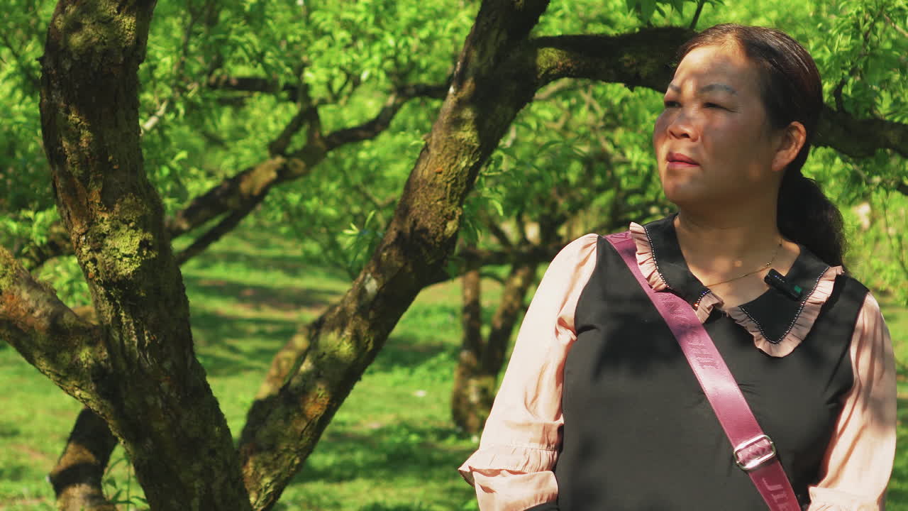 A woman talks calmly with a tree behind her in a natural outdoor setting. Ideal for interviews, storytelling, or nature-themed content with a peaceful, grounded vibe.