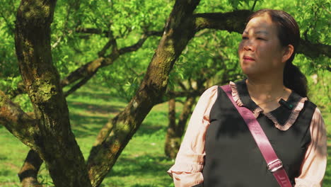 a woman talks calmly with a tree behind her in a natural outdoor setting. ideal for interviews, storytelling, or nature-themed content with a peaceful, grounded vibe.