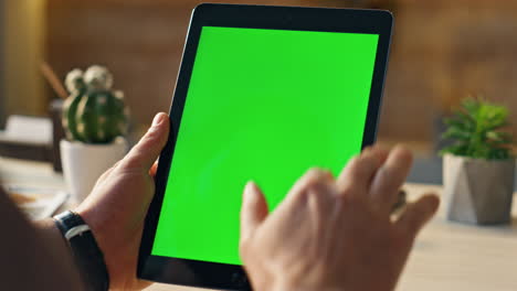 man working mockup tablet in office close up. male hands holding green screen