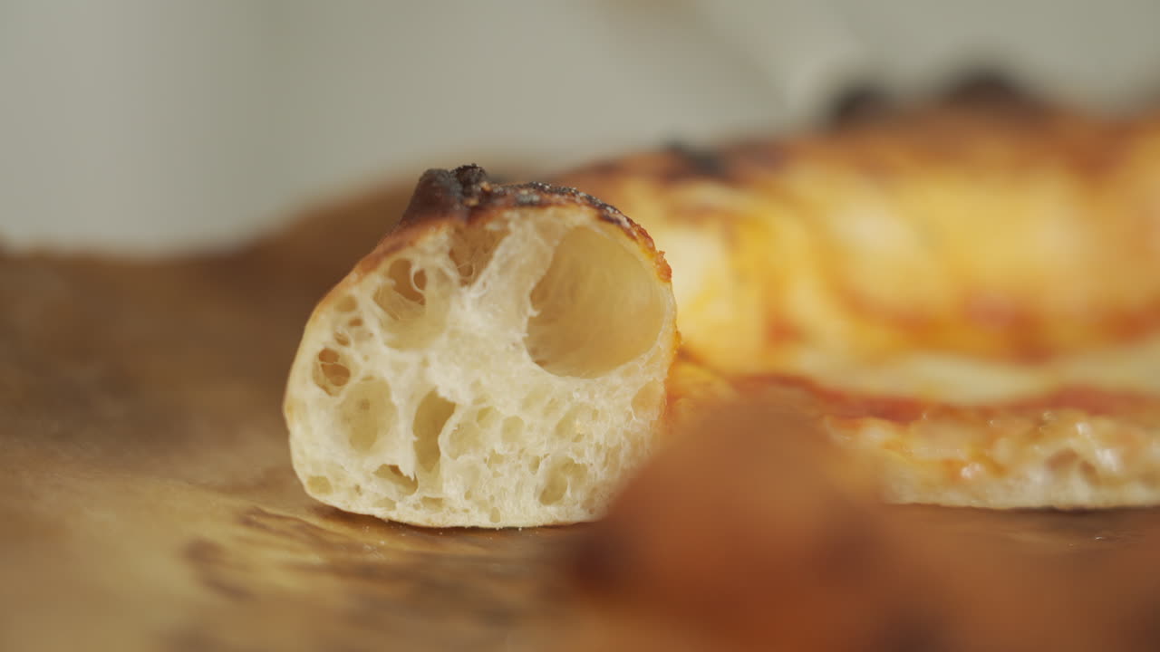 나폴리 마르게리타 피자 한 조각을 가져다가 알베올레이트 크러스트 "코르니시오네"를 드러냄