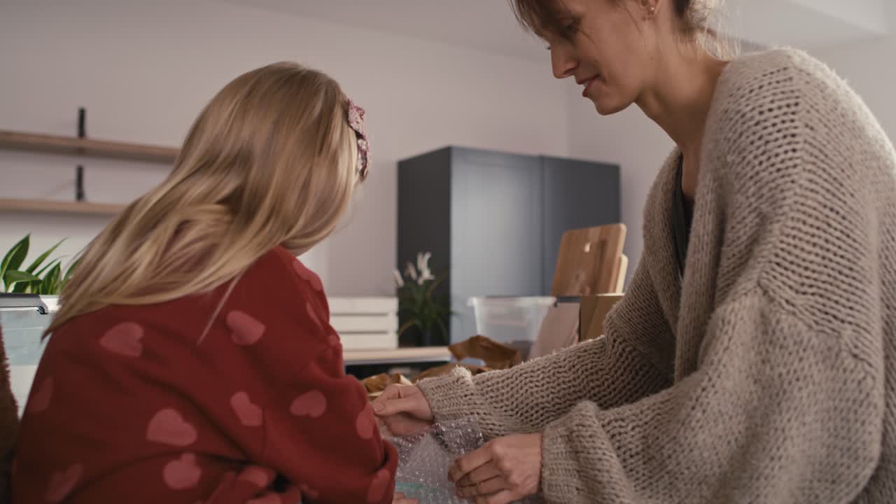 madre y hija caucásicas empacando cosas de cocina.