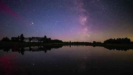 Nachthimmel-Voller-Sterne,-Die-Auf-Ruhigem-Seewasser-Reflektieren,-Mit-Fahrzeuglichtern,-Die-In-Der-Ferne-Leuchten