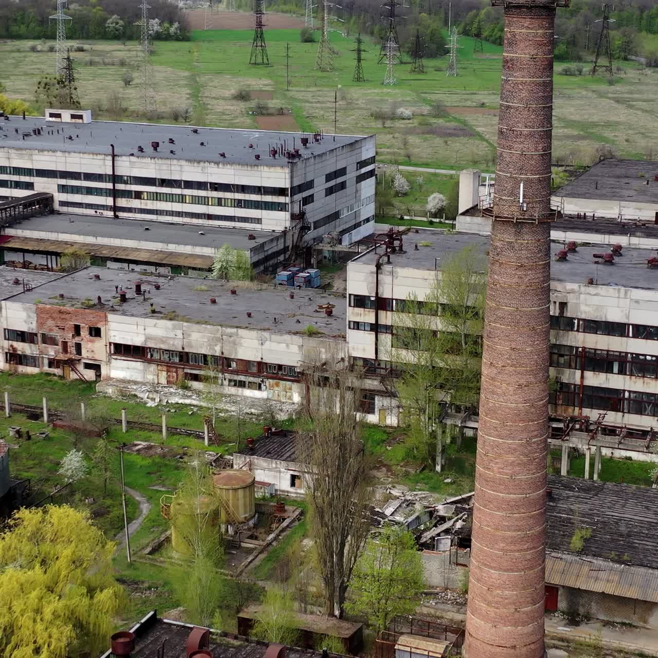 Panoramic view of an old factory. Abandoned territory of industrial plant with large brick pipe. Ruined manufacting in springtime. Aerial view
