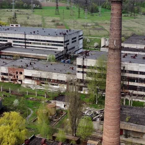 Panoramic view of an old factory. Abandoned territory of industrial plant with large brick pipe. Ruined manufacting in springtime. Aerial view