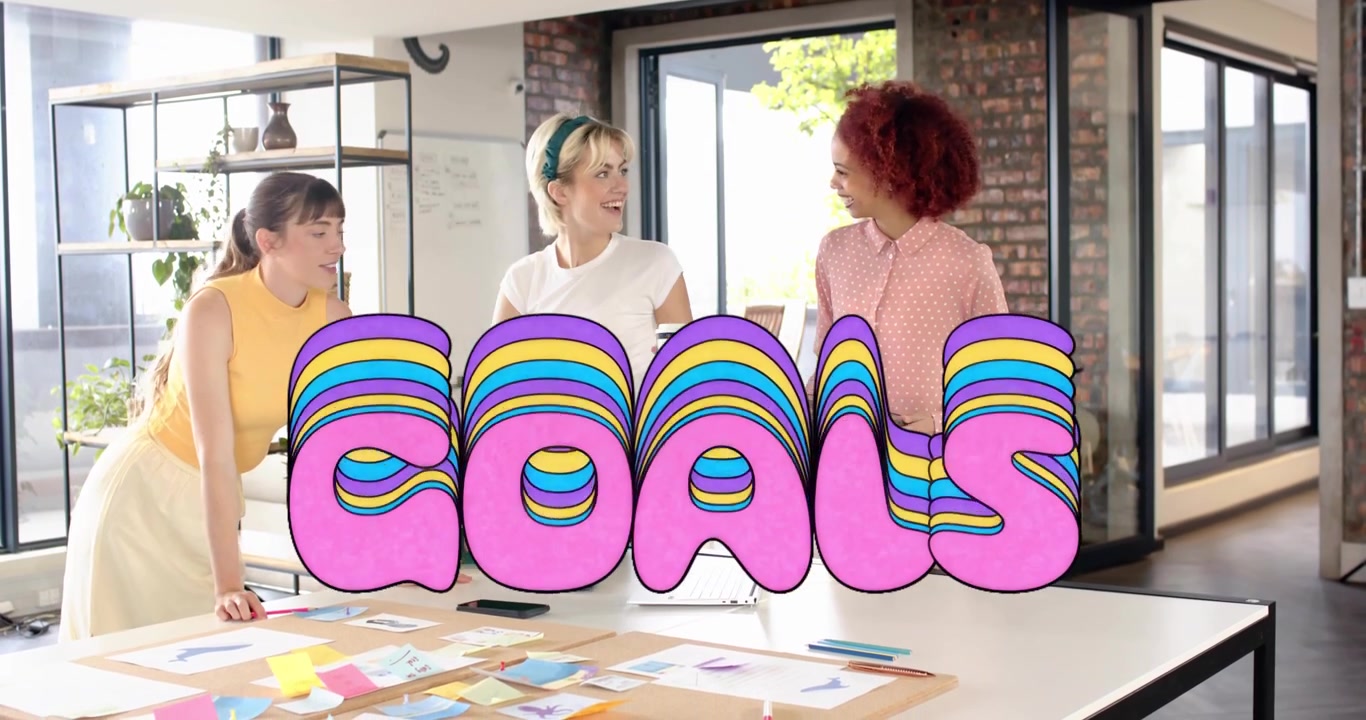 Design team planning around table woman entering with tablet starting GOALS text tagging stickies