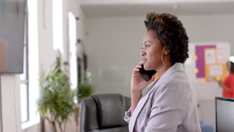 Glückliche-Afroamerikanische-Geschäftsfrau,-Die-Im-Büro-Auf-Dem-Smartphone-Spricht,-Kopierraum,-Zeitlupe