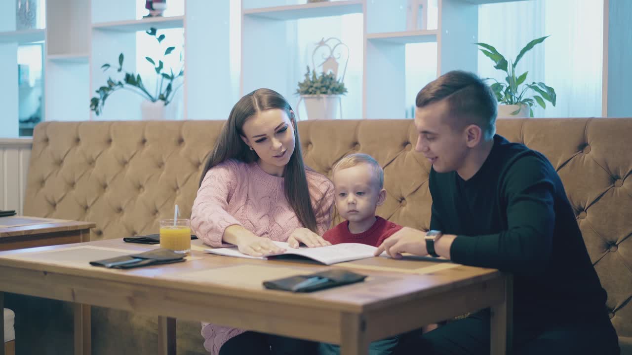 familia emocionante mira el menú sentado en el sofá de cuero marrón