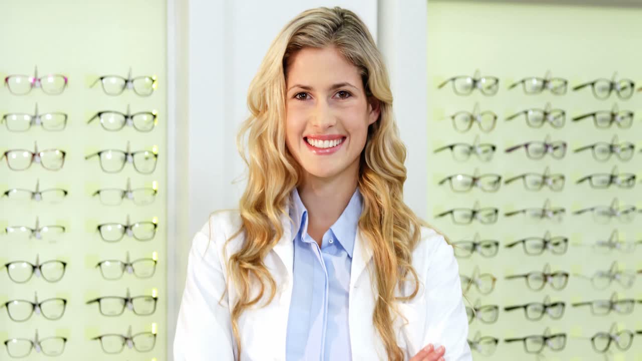 Beautiful optometrist standing with arms crossed at ophthalmology clinic