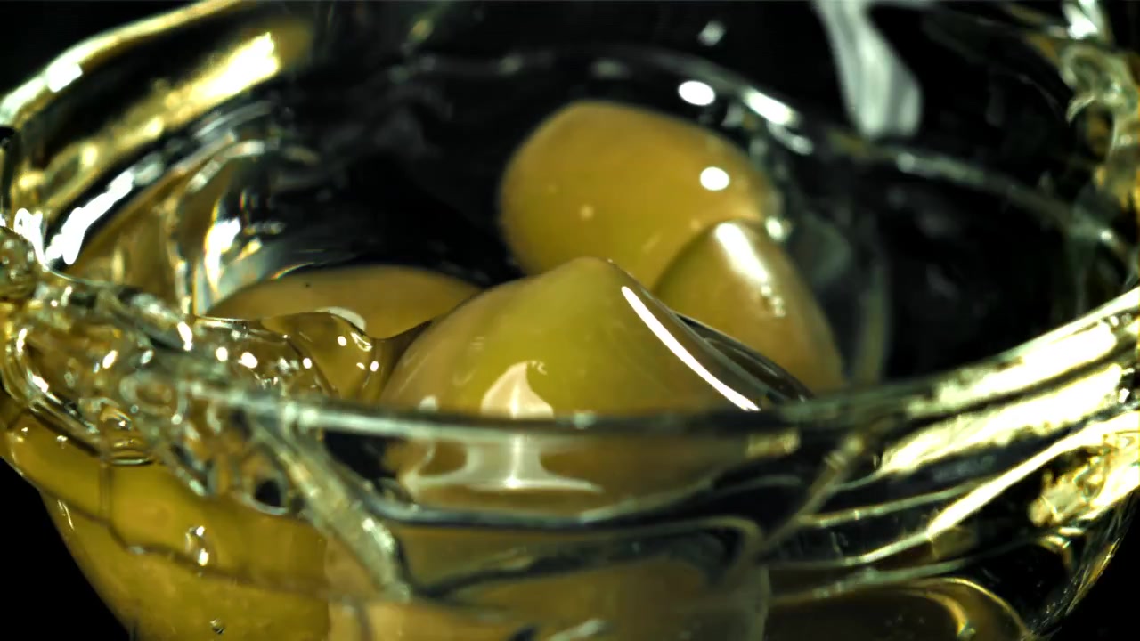Rallentatore di olive verdi che schizzano in una ciotola di liquido