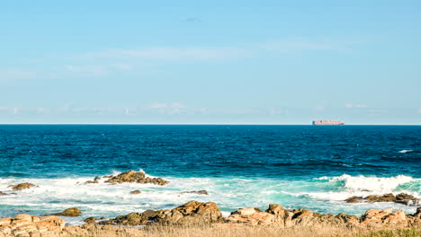 timelapse of container ship cruising on horizon as waves crash in foreground