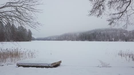 Deslizamiento-Lento-Sobre-Una-Playa-De-Lago-Nevado-En-Invierno-Con-Fondo-Brumoso