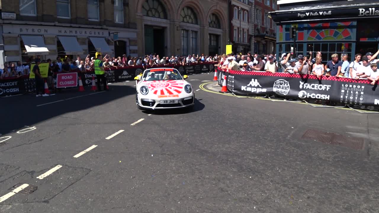 Ford Mustang police car and beautiful porsche cruising on London roads and presenting cars during Gumball3000 outdoor show.