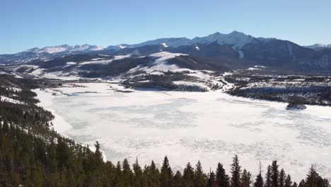 Frozen-lake-with-the-Rocky-Mountains-in-the-background,-dolly-aerial