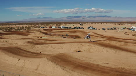 dirt bike riders catching air while jumping off ramp on dirt track, slow motion