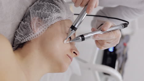 woman receiving a facial treatment with a micro-needling device at a clinic.