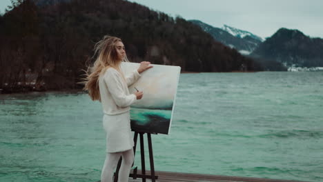 woman painting landscape by a lake