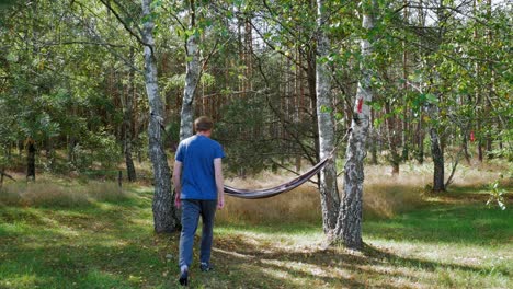 Hombre-Caucásico-Disfrutando-Y-Relajándose-En-Una-Hamaca-Colgada-Sobre-árboles-En-Un-Bosque-Tranquilo---Plano-Medio