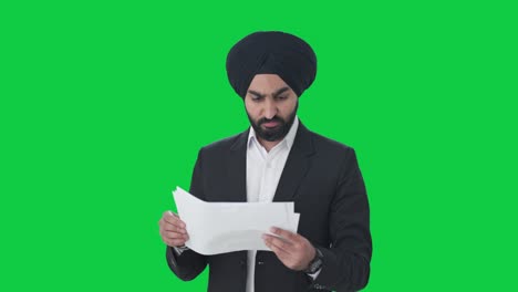 stressed sikh indian businessman reading company reports green screen