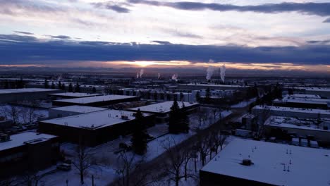 winter sunset in an industrial area with steaming factory pipes