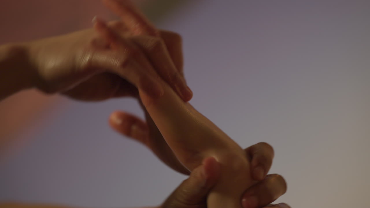 Close up shot of massage therapist's hands massaging a woman's hand, interior