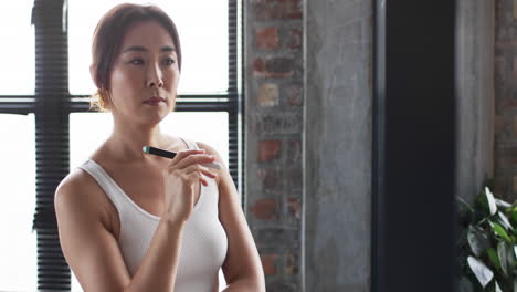 asian businesswoman in white tank top holds a pen, looking pensive, with copy space