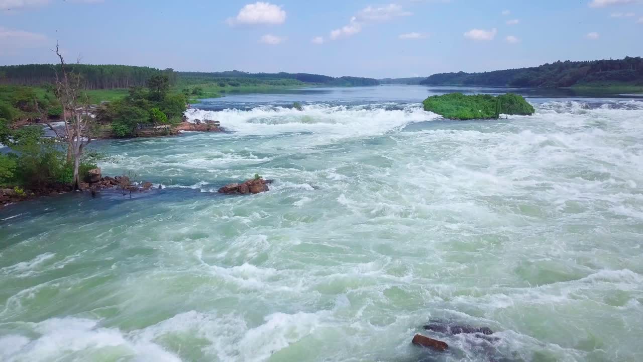 River Nile rapids flowing powerfully through lush green landscape in Uganda, Africa, creating a breathtaking aerial view of nature's raw beauty and dynamic energy, drone reveal shot