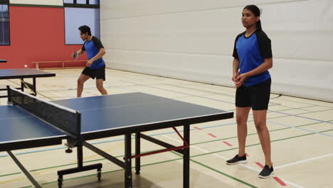 playing table tennis, man serving ball while woman preparing to return