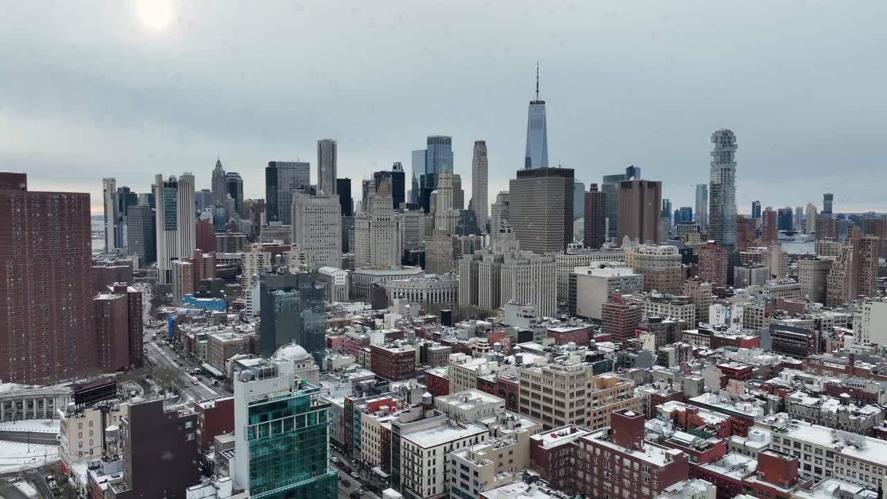 Snefnug, der flyver hen over Manhattans skyline om vinteren og afslører tæt højhusarkitektur, kold grå himmel og en filmisk byatmosfære over New York City. Bredt luftfoto.