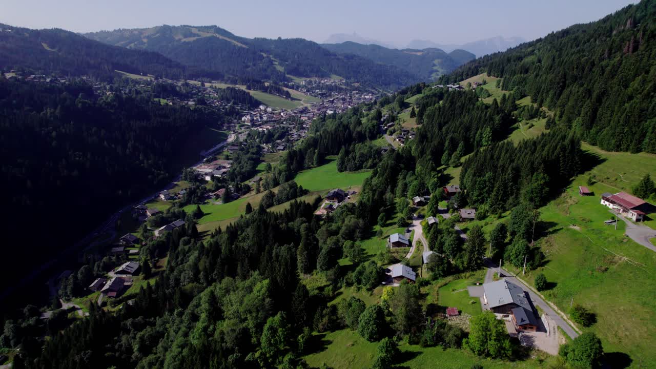 Aerial view of holiday winter sports region during summer with chalets in lush greenery against the mountain side