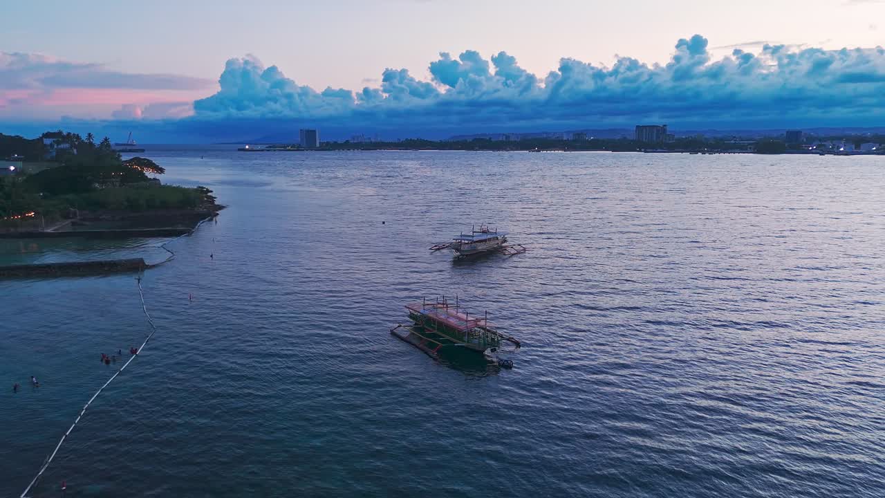 Peaceful 4K drone footage of tropical boats floating on calm ocean water at dusk in the Philippines. Perfect for travel, cinematic, and lifestyle projects