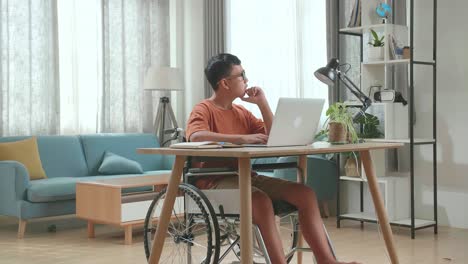 young asian boy sitting working on laptop computer and thinking about something then raising his index finger, eyes wide open at home