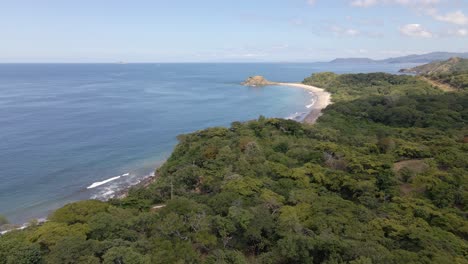 Aerial-Panning-Shot-Above-Very-Dense-Trees-Looking-Out-Onto-The-Coast-And-Sea