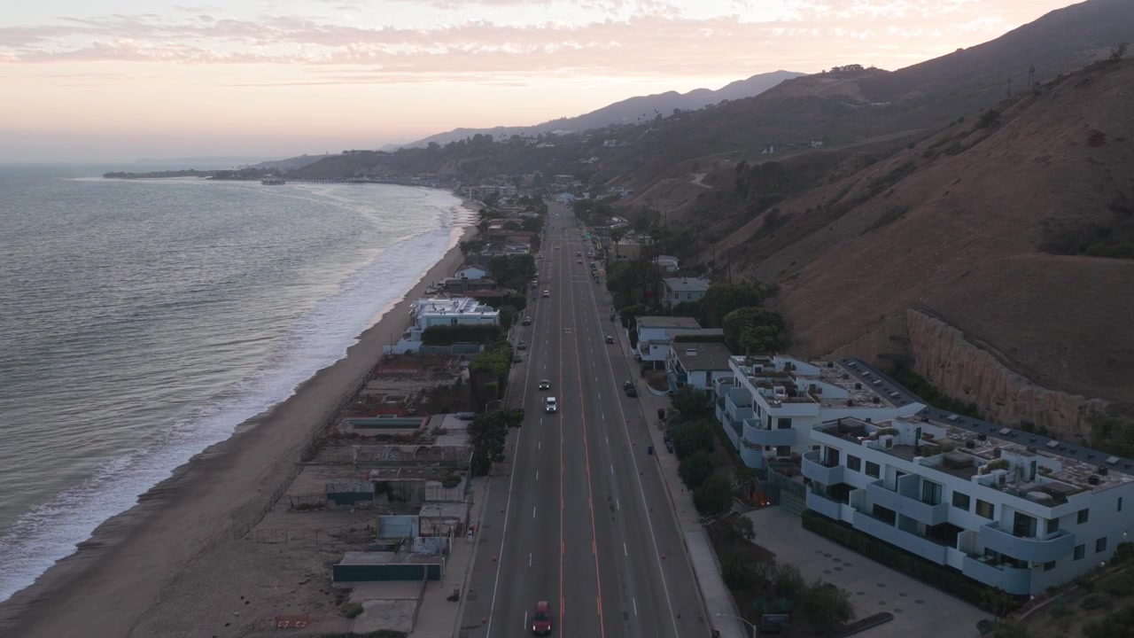 Ripresa aerea in discesa che sorvola la Pacific Coast Highway al tramonto a Malibu, California. 4K